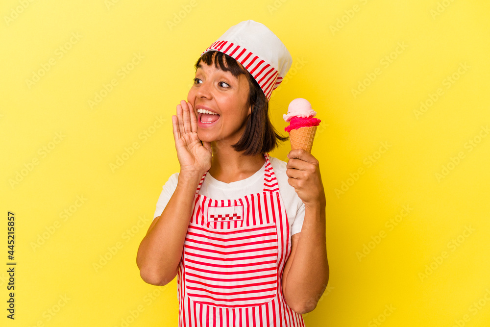 Young mixed race ice cream maker woman holding an ice cream isolated on yellow background shouting and holding palm near opened mouth. Young mixed race ice cream maker woman holding an ice cream isolated on yellow background shouting and holding palm near opened mouth.
