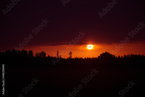 The summer sun rising over a rural scenery. Sunrise landscape. Summertime scenery of Northern Europe.