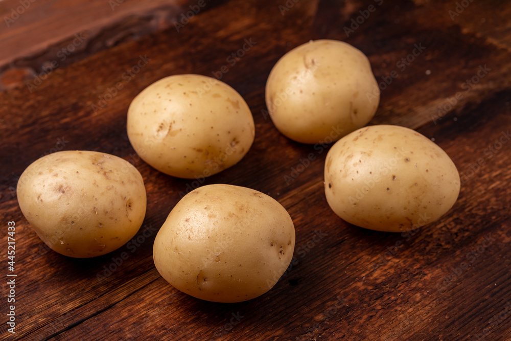 Tubers of large young potatoes on a wooden background. Tubers of large young potatoes on a wooden background.