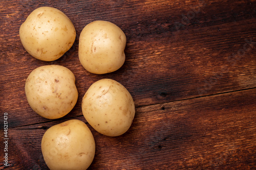 Tubers of large young potatoes on a wooden background.