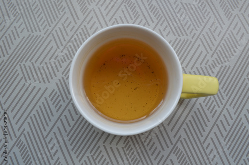 Yellow tea in a white and yellow tea mug on the table
