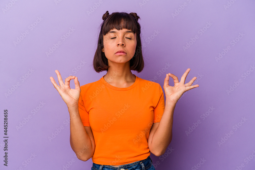 Young mixed race woman isolated on purple background relaxes after hard working day, she is performing yoga. Young mixed race woman isolated on purple background relaxes after hard working day, she is performing yoga.