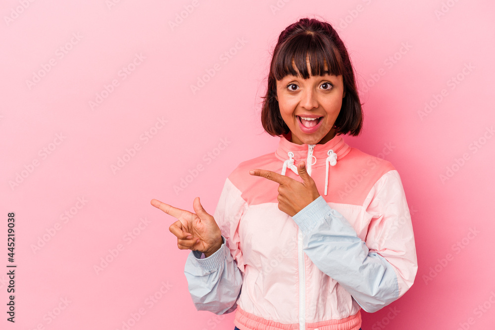 Young mixed race woman isolated on pink background excited pointing with forefingers away. Young mixed race woman isolated on pink background excited pointing with forefingers away.
