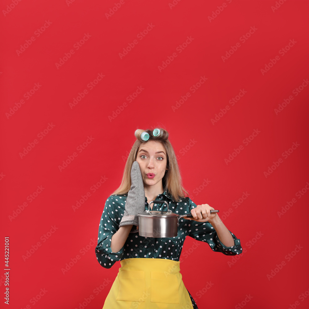 Obraz premium Young housewife with saucepan on red background
