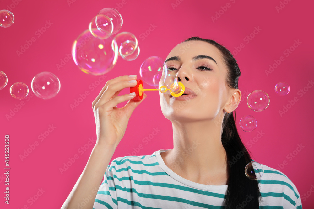 Young woman blowing soap bubbles on pink background Young woman blowing soap bubbles on pink background