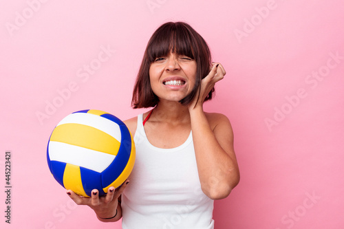 Young mixed race woman playing volleyball isolated on pink background covering ears with hands.
