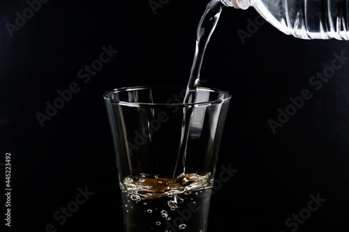 Pouring water into the glass on a black background. 