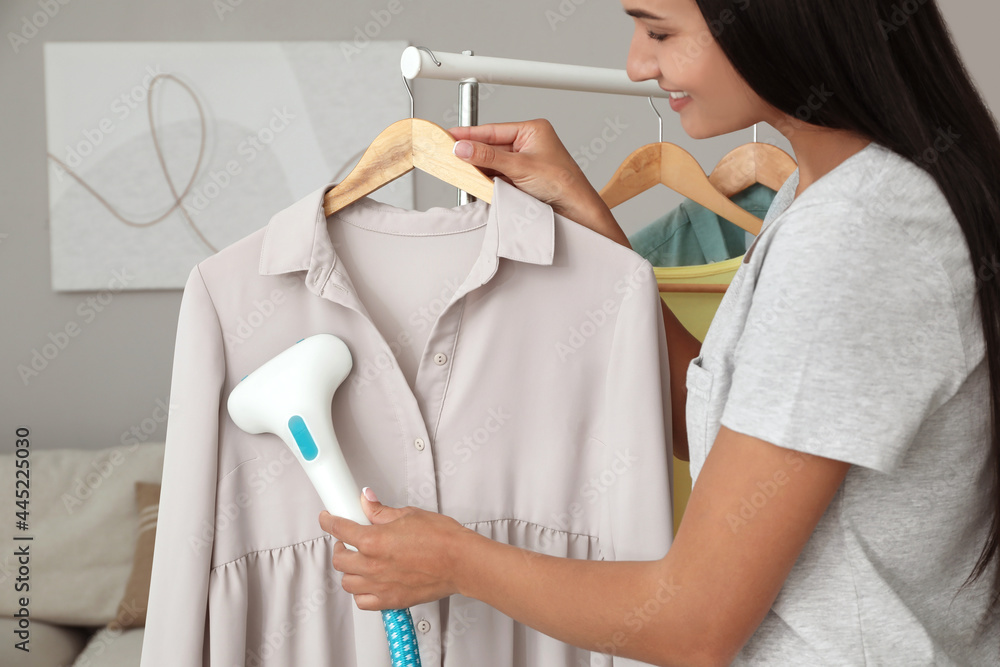 Woman steaming blouse on hanger at home, closeup Woman steaming blouse on hanger at home, closeup