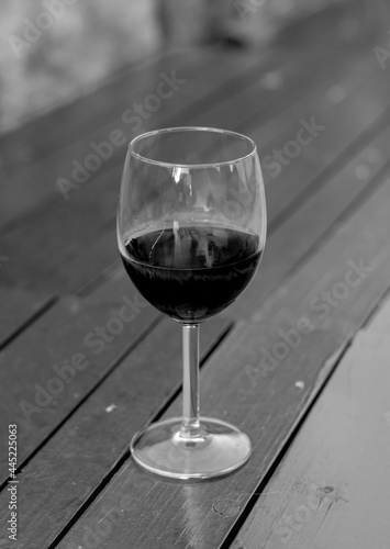 Glass of red wine on the wooden table. Black and white. Selective focus.