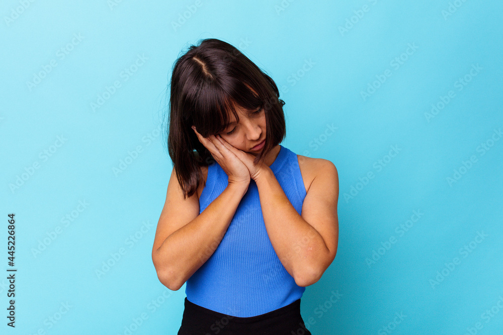 Young mixed race woman isolated on blue background yawning showing a tired gesture covering mouth with hand. Young mixed race woman isolated on blue background yawning showing a tired gesture covering mouth with hand.