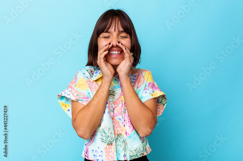 Young mixed race woman isolated on blue background saying a gossip, pointing to side reporting something.