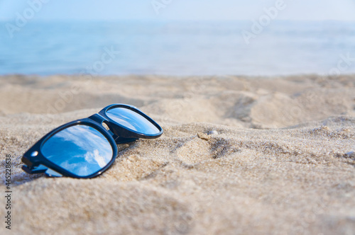 Mirror sunglasses on the sand beach with blue sky reflection