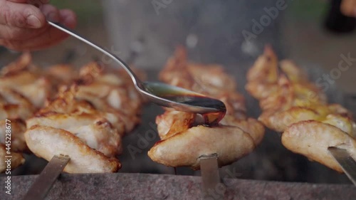 Chief pours sauce on grilling checken wings. Hd Slowmo shot photo