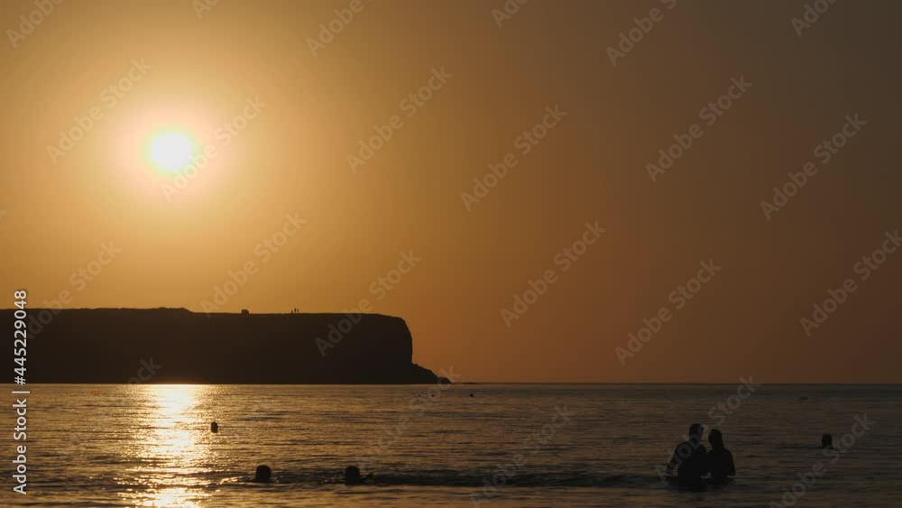 Silhouettes of people swimming in the sea at sunset. Silhouettes of people swimming in the sea at sunset.