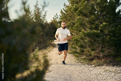 Young muscular male athlete running up the hill