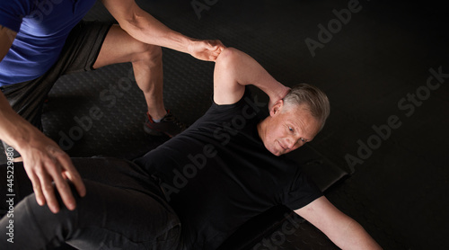 Mature man being assisted, cross over ab crunch on mat with copy space
