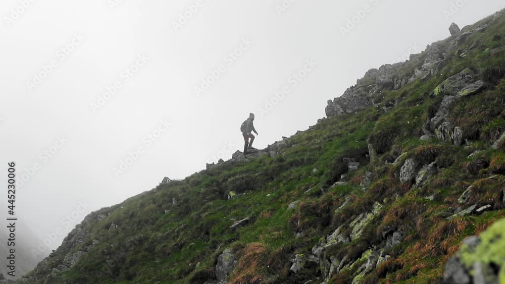 Amazing landscape with a hiker walking on mountain cliffs in a foggy day Amazing landscape with a hiker walking on mountain cliffs in a foggy day