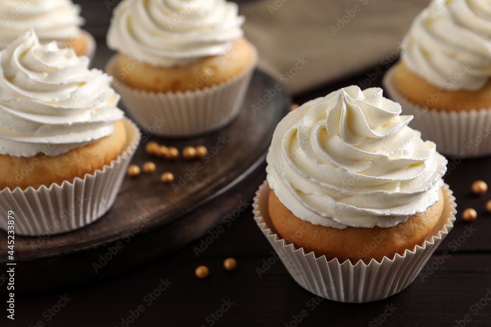 Delicious cupcakes with white cream on wooden table, closeup