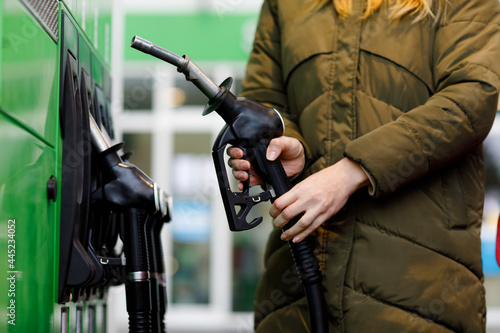 Close-up of hands of woman at self-service gas station, hold fuel nozzle and refuel the car with petrol, diesel, gas. Close up of filling auto with gasoline or benzine. Self service gas pump
