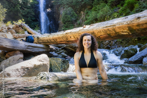 Adult Caucasian Woman hiker swimming in glacier water at Norvan Falls during hot and sunny summer day. Canadian Nature Background. Lynn Valley, North Vancouver, British Columbia, Canada. photo
