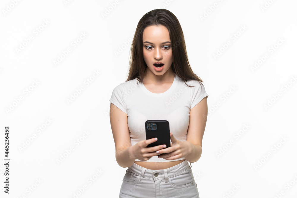 Portrait of a surprised attractive girl holding mobile phone and looking at camera isolated over white background Portrait of a surprised attractive girl holding mobile phone and looking at camera isolated over white background
