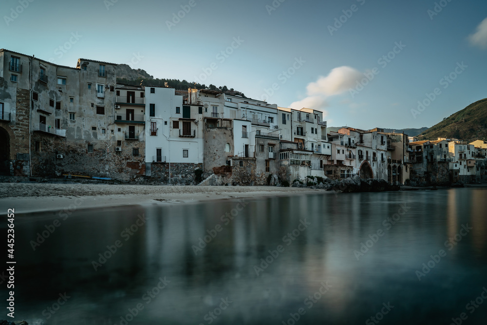 Sunrise in harbor of Cefalu, Sicily, Italy, old town panoramic view with colorful waterfront houses, sea and La Rocca cliff.Attractive summer cityscape,traveling concept background.Italian vacation.