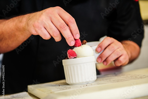 Cheef's hands decorating ise cream with berry