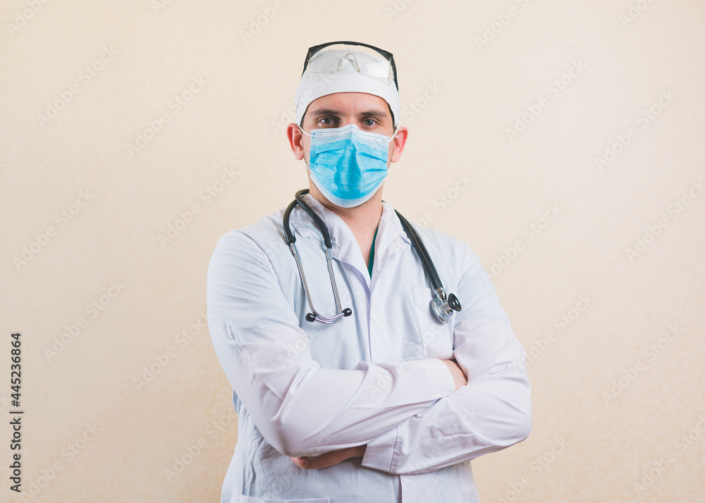 Young doctor in white suit, protective glasses, stethoscope and protective breathing mask with his hands on his chest isolated Young doctor in white suit, protective glasses, stethoscope and protective breathing mask with his hands on his chest isolated