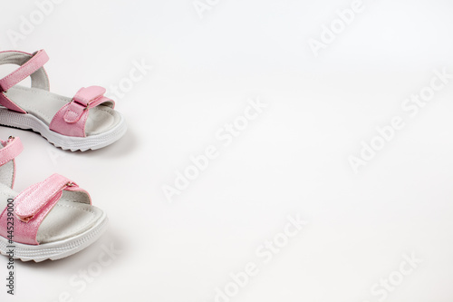 Pink children's sandals made of shiny leather with Velcro fasteners, flat white soles, isolated on a white background. A pair of fashionable children's sandals for a comfortable walk. 