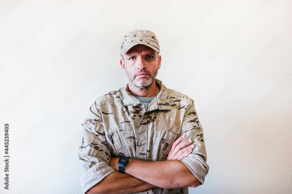 Fototapeta premium Caucasian man in camouflaged army uniform crossing arms