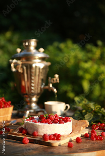 Fototapeta Naklejka Na Ścianę i Meble -  Summer atmosphere. Russian cuisine. Dacha, nature. Cottage cheese pie, cake with fresh berries: red currants and raspberries on an old wooden table. Samovar with a cup. Background image, copy space
