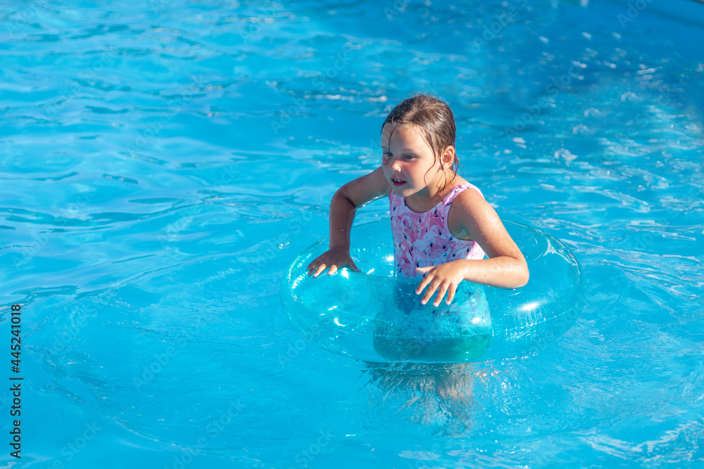 the girl holds on to a transparent blue inflatable circle with her hands, has a good time on vacation in a hotel on a sunny day. 