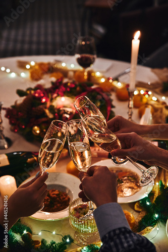 Cheers with champagne. People clink glasses of champagne at the holiday table on New Year's Eve. High quality photo