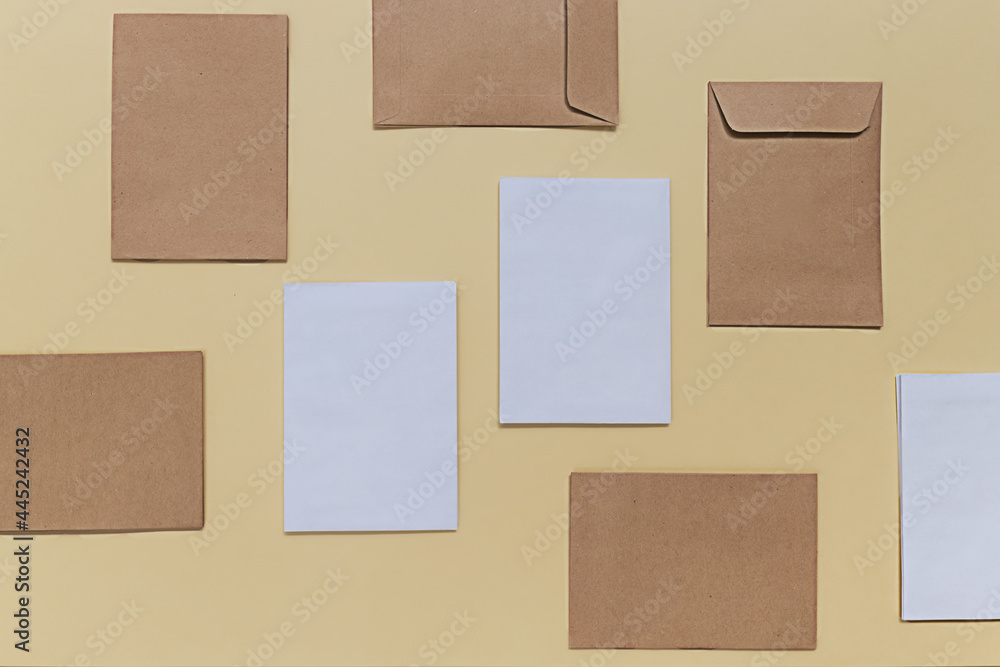 Back to school creative concept. Blank mock up with white and beige envelopes on a yellow paper background. Minimalist flat lay, top view composition. Back to school creative concept. Blank mock up with white and beige envelopes on a yellow paper background. Minimalist flat lay, top view composition.