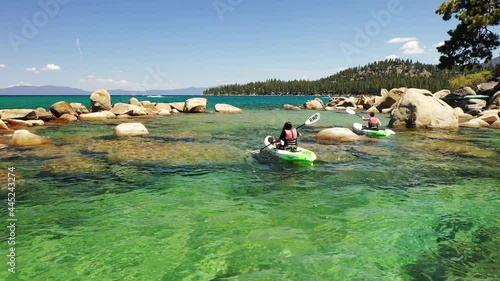 Aerial view of a couple kayaking on Lake Tahoe in California. The water is turquoise and mountains can be seen in the background with blue skies.