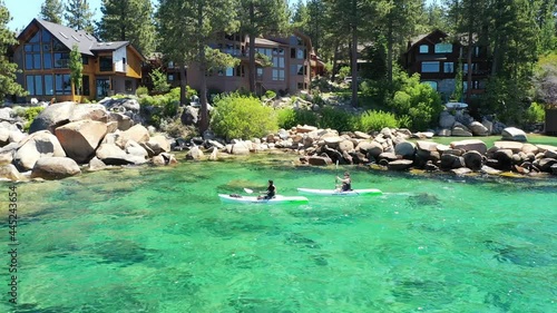 Aerial view of a couple kayaking on Lake Tahoe in California. The water is turquoise and mountains can be seen in the background with blue skies.