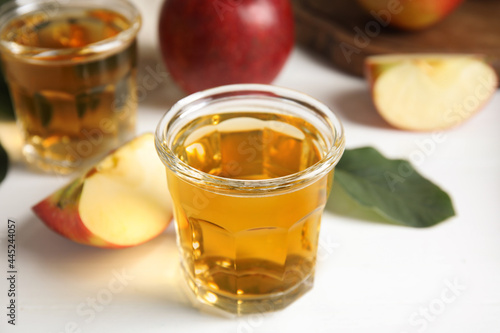 Glass of delicious apple cider on white table