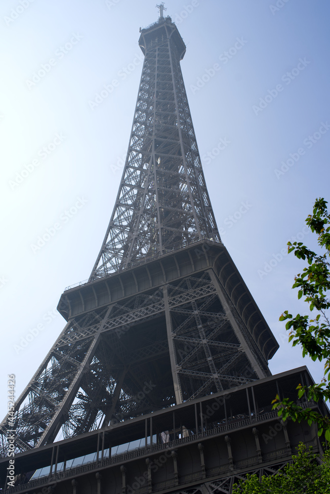 Eiffel tower at high noon at springtime with cloudy blue sky background. Photo taken May 1st, 2019, Paris, France.