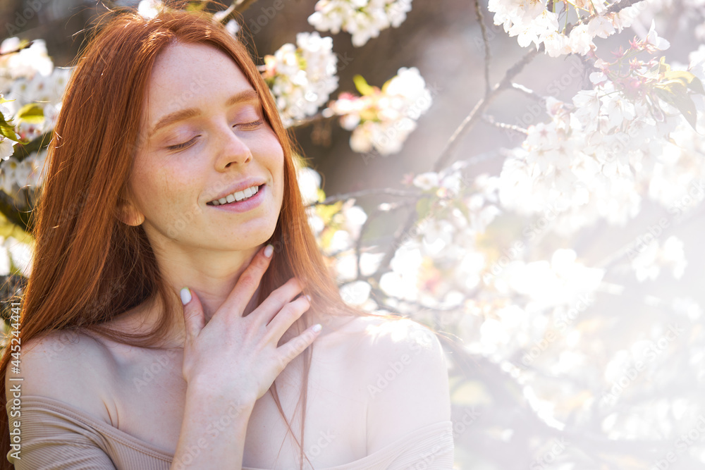 beautiful redhead woman in blossoming garden touching face sensually, posing at camera. attractive woman with natural make-up enjoy time outdoors, in romantic beautiful place at spring beautiful redhead woman in blossoming garden touching face sensually, posing at camera. attractive woman with natural make-up enjoy time outdoors, in romantic beautiful place at spring