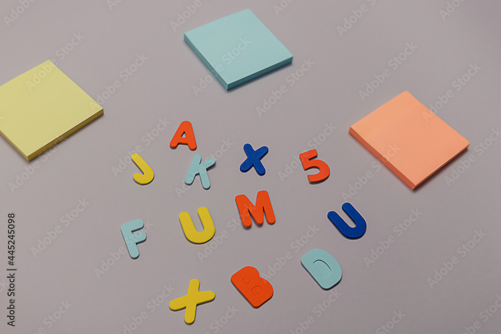 Back to school creative concept. Colorful stickers and vibrant foam letters in a chaotic manner lying on purple paper background. Flat lay. Back to school creative concept. Colorful stickers and vibrant foam letters in a chaotic manner lying on purple paper background. Flat lay.
