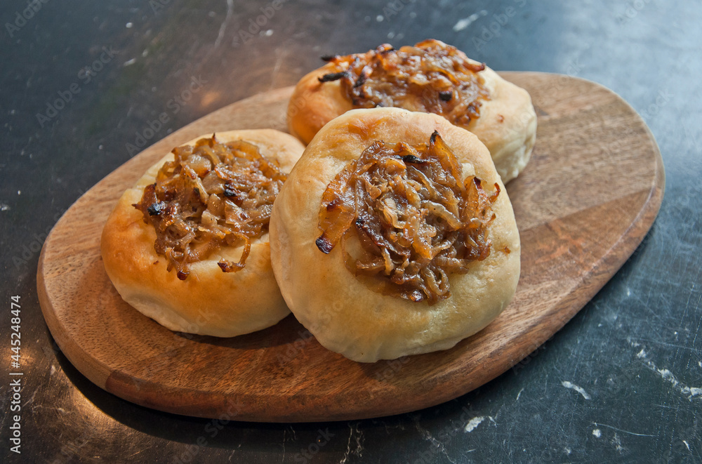Tasty onion roll on wooden plate