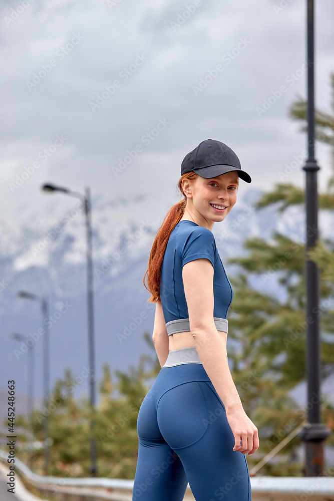 Happy young woman smiling after workout exercise. female is looking at camera. Beautiful young redhead caucasian woman feeling energetic after yoga and exercise in nature