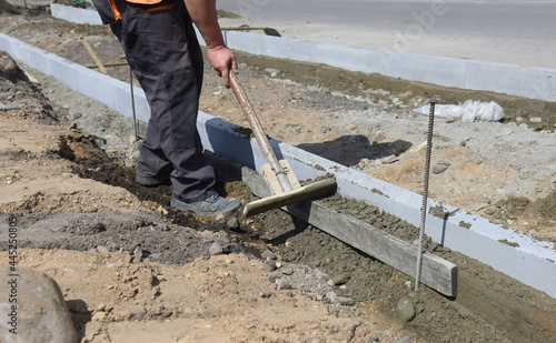 Workers install concrete curbs in cement.