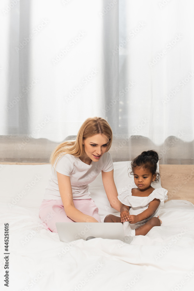 happy mother and adopted african american kid watching movie on laptop in bedroom happy mother and adopted african american kid watching movie on laptop in bedroom