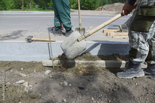 A worker throws cement with a shovel, road construction.