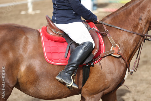 Old leather saddle with stirrups for show jumping race. Equestrian sport event background © acceptfoto