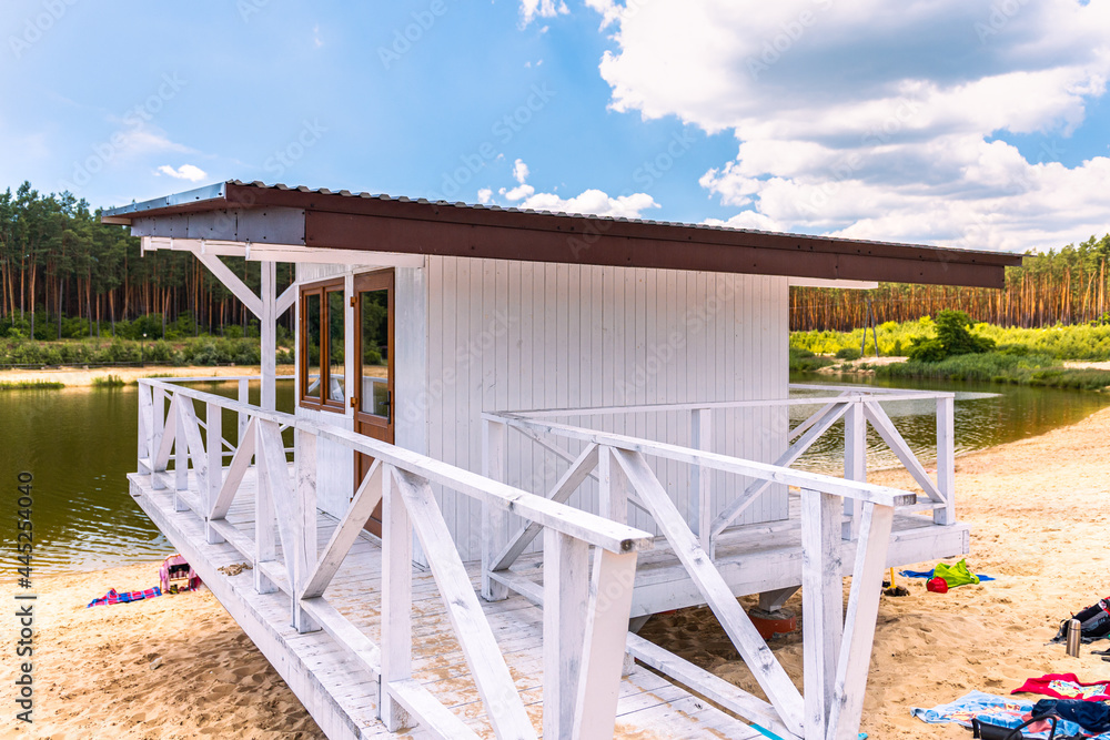 White, wooden lifeguard booth situated on sand beach next to the lake on a beautiful, sunny day White, wooden lifeguard booth situated on sand beach next to the lake on a beautiful, sunny day