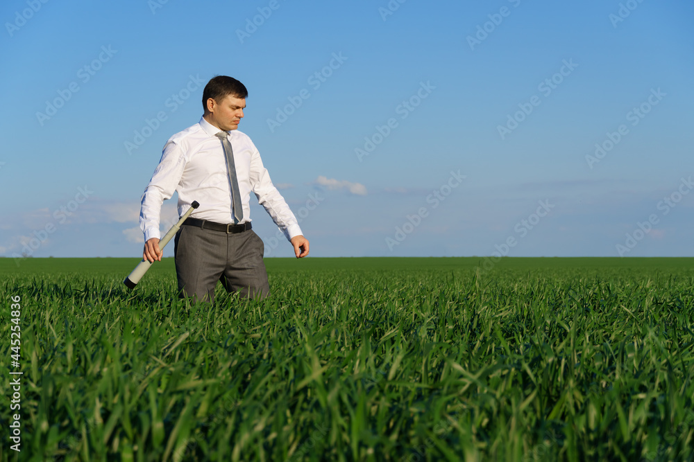 businessman poses with a spyglass, he looks into the distance and looks for something, green grass and blue sky as background businessman poses with a spyglass, he looks into the distance and looks for something, green grass and blue sky as background