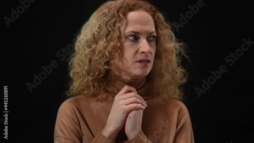 Portrait of anxious Caucasian woman thinking talking to herself at black background. Worried lady rehearsing speech. Anxiety and public speaking concept photo