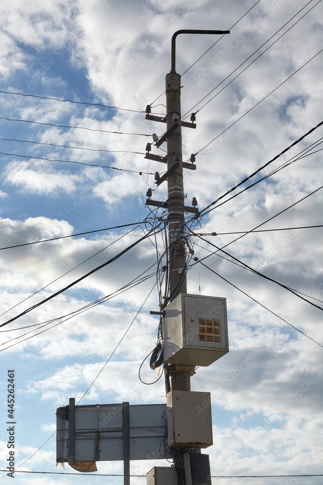 Street lighting poles covered with wires. A pole with a lantern, wires and a stormy sky. Cables or wires are connected between each concrete electricity post.